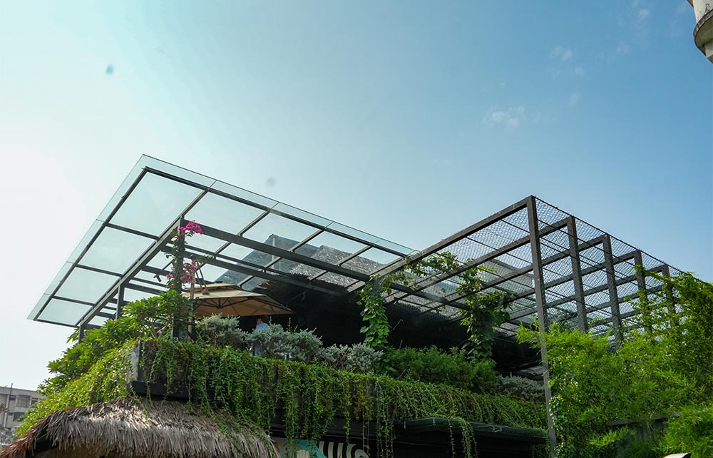 Modern glass pergola design for a contemporary home terrace in Kerala.